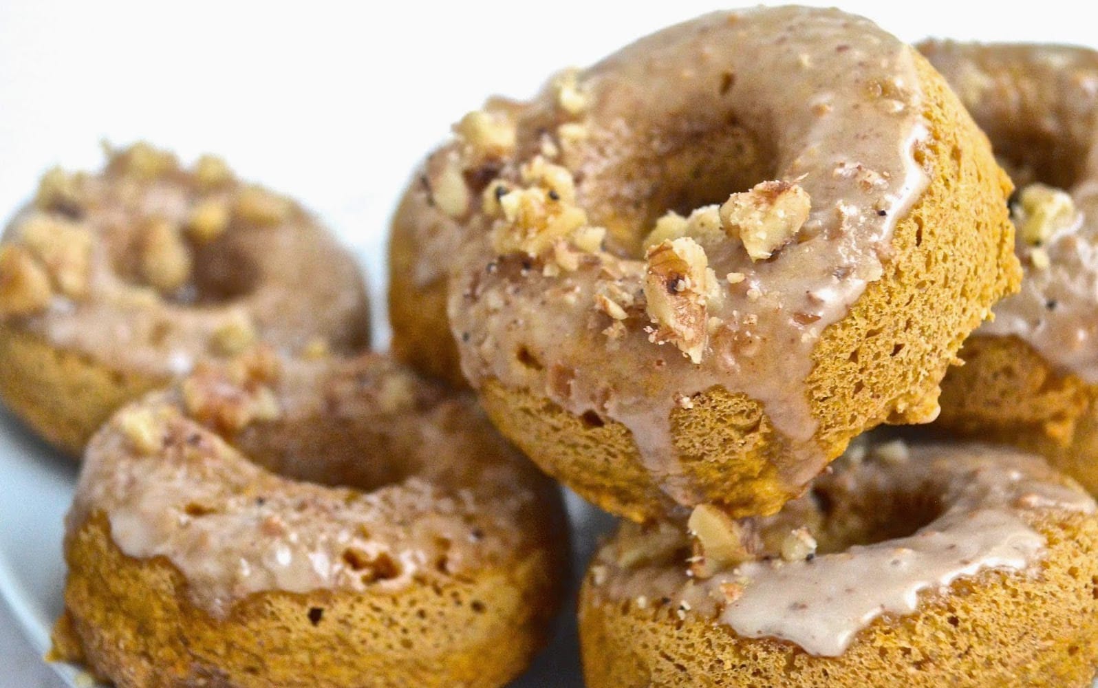Vegan Pumpkin Spice Doughnuts With Maple Glaze in a pile
