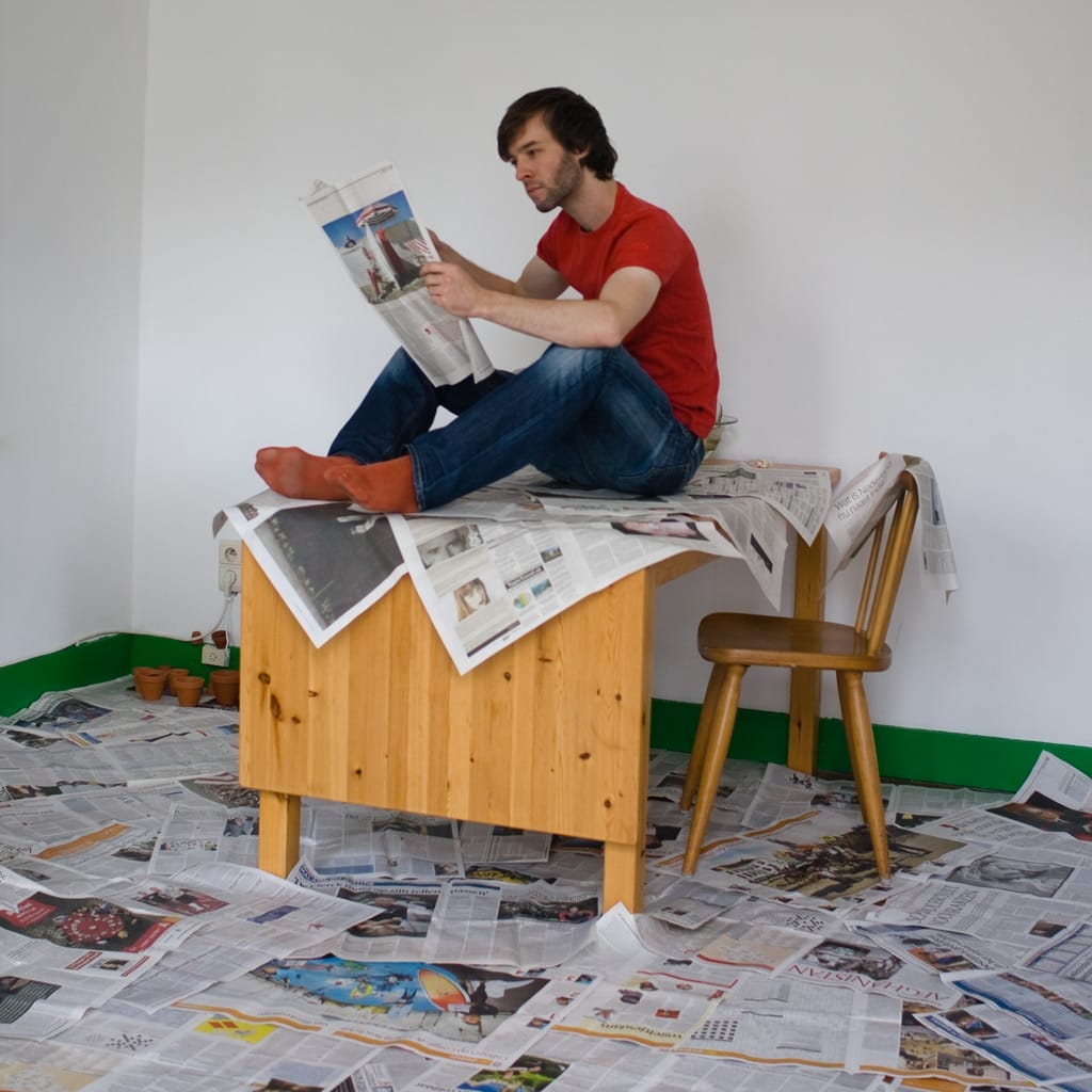 Man sitting on newspapers and reading a newspaper