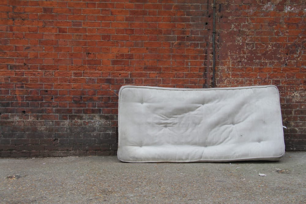 old mattress against a brick red wall