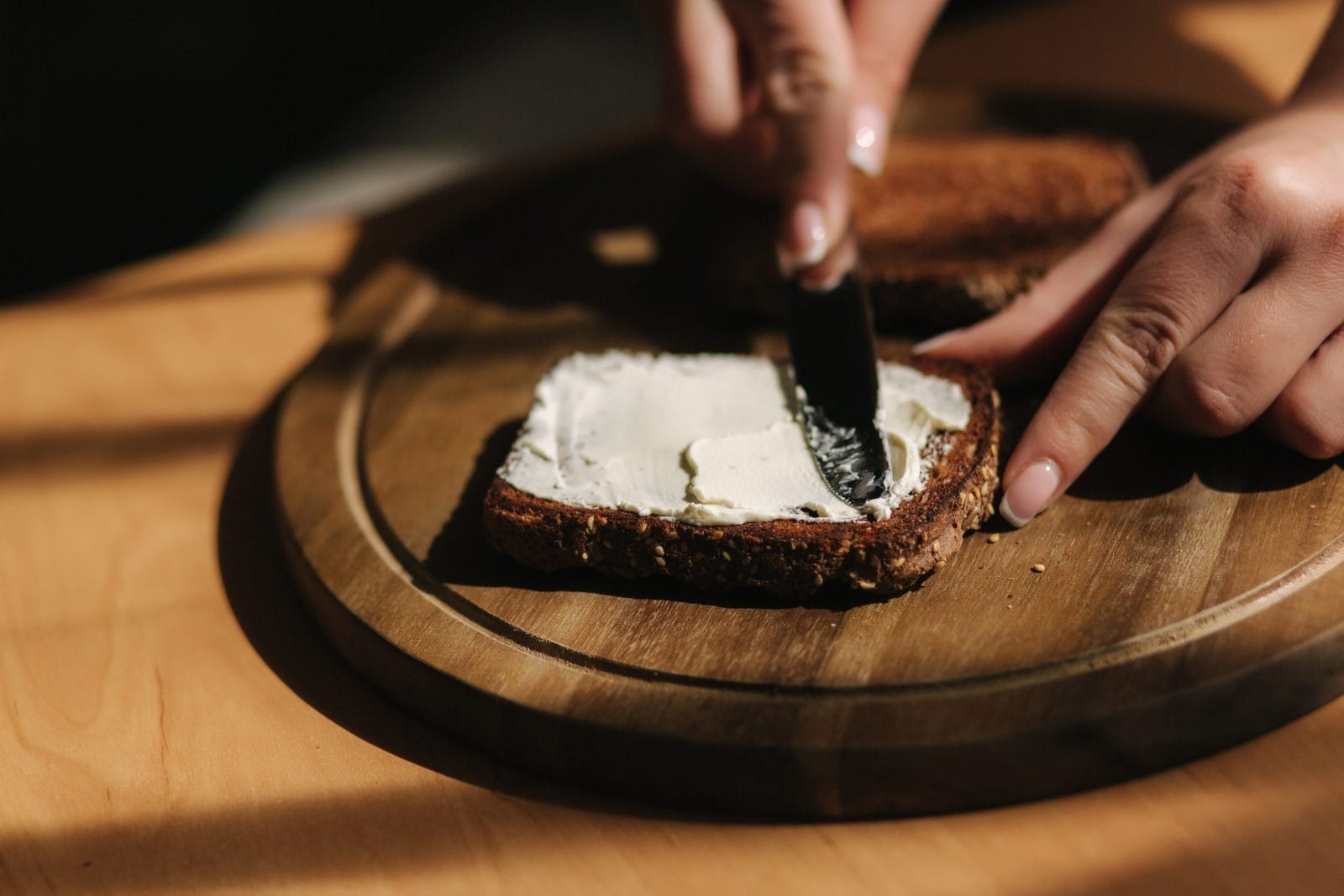 someone smearing spread on piece of toast