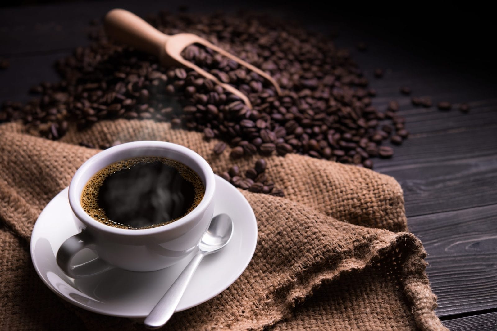 Black coffee with coffee beans behind it