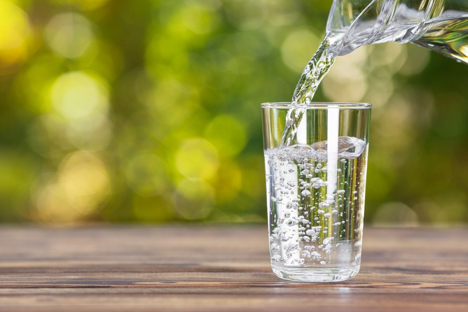 glass cup filling with water on a table with green background