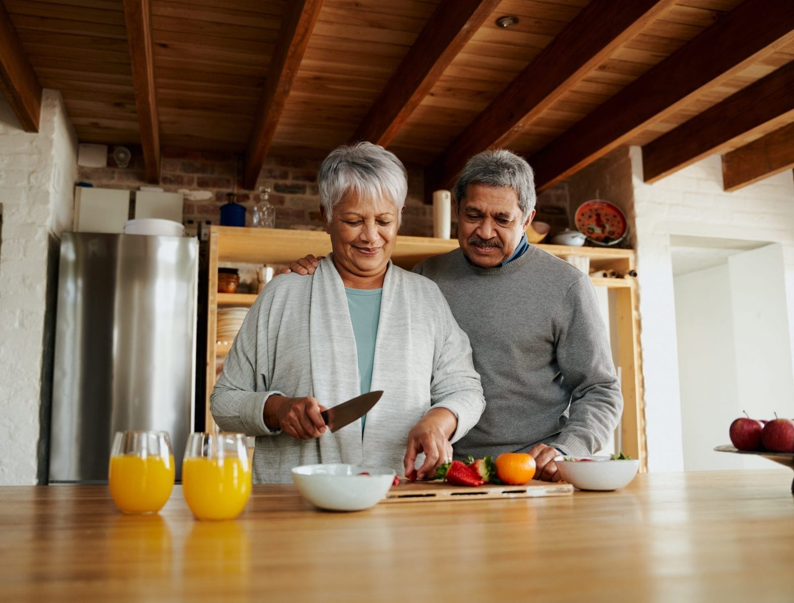 Elderly couple cutting fruit in a kitchen