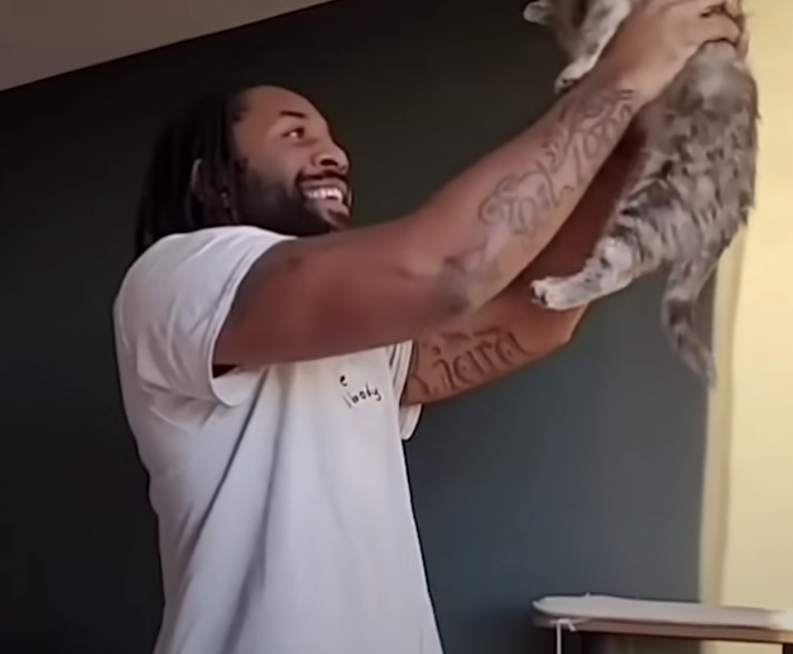 Abdul holding a cat in front of him