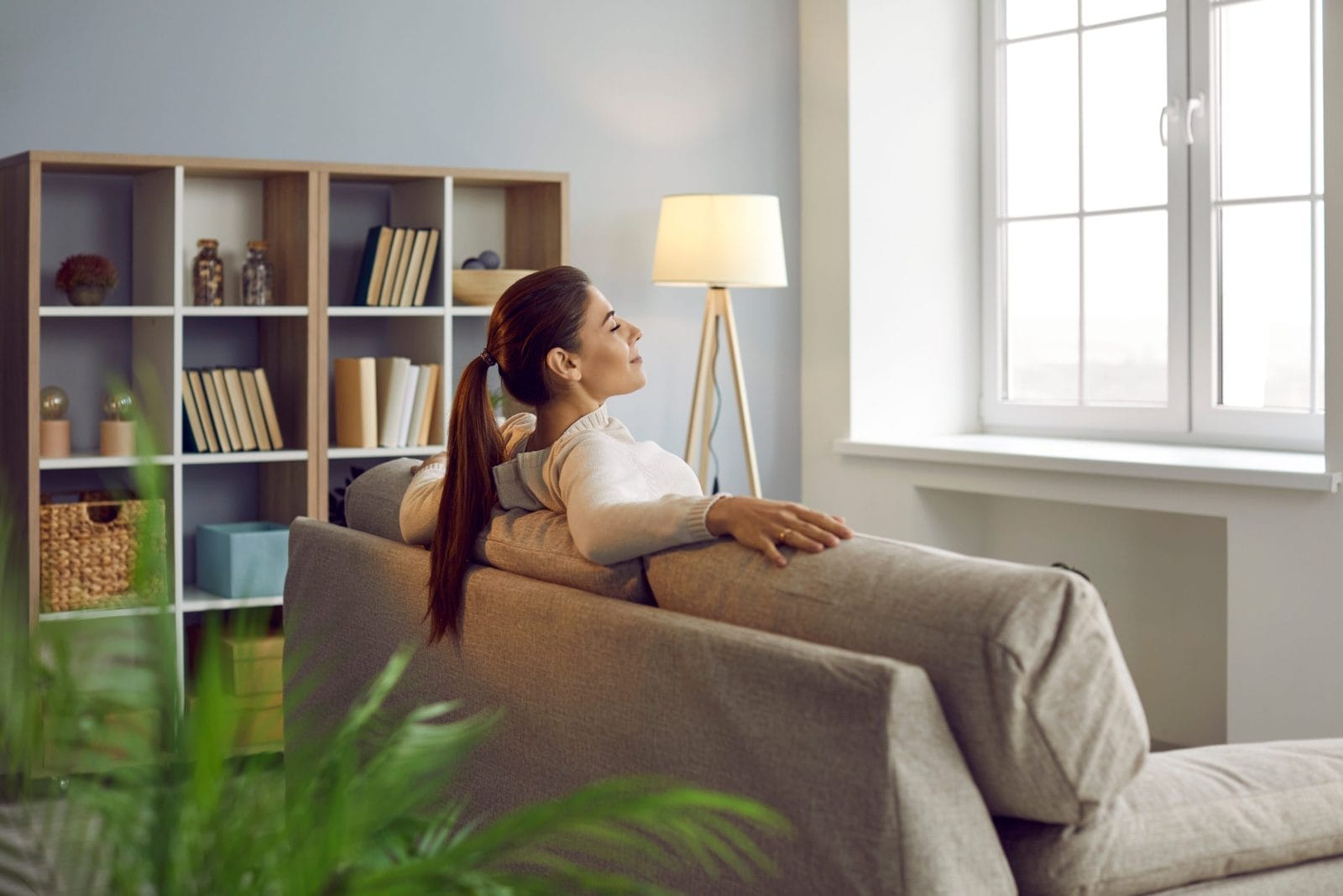 Woman sitting on couch with arms on the back