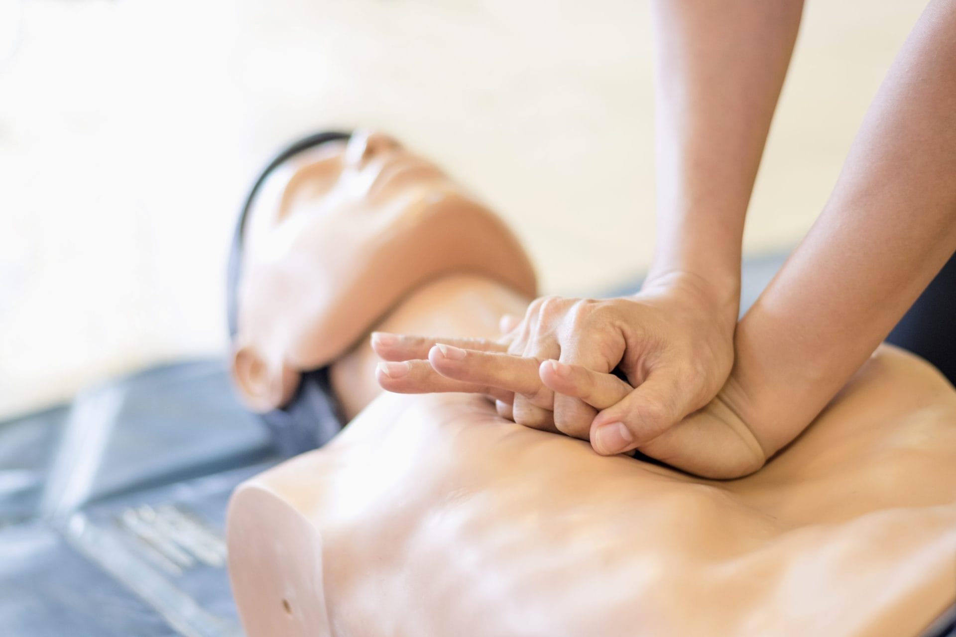Someone doing chest compressions on CPR doll