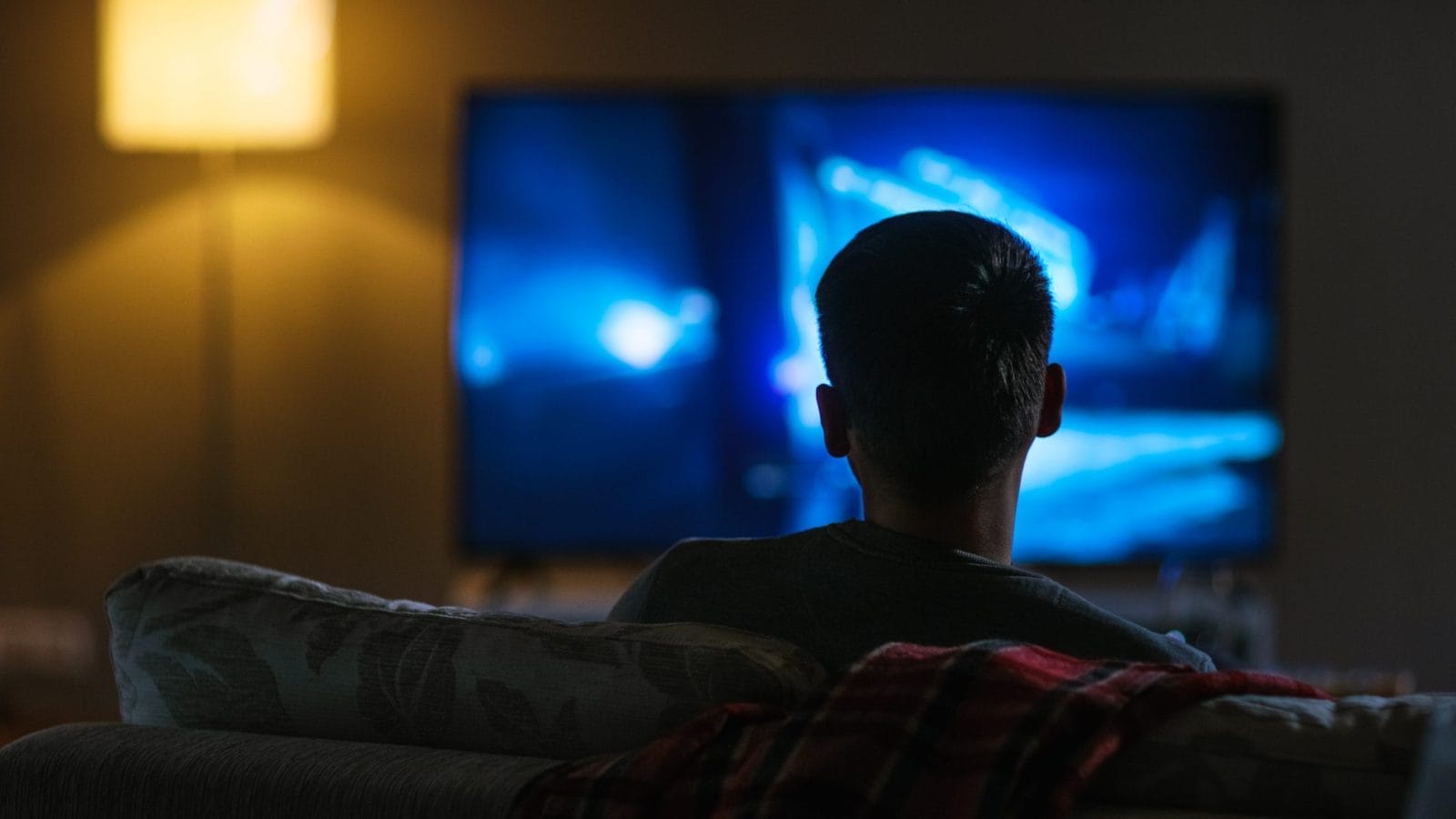 Back View of a Man Sitting on a Couch Watching Movie