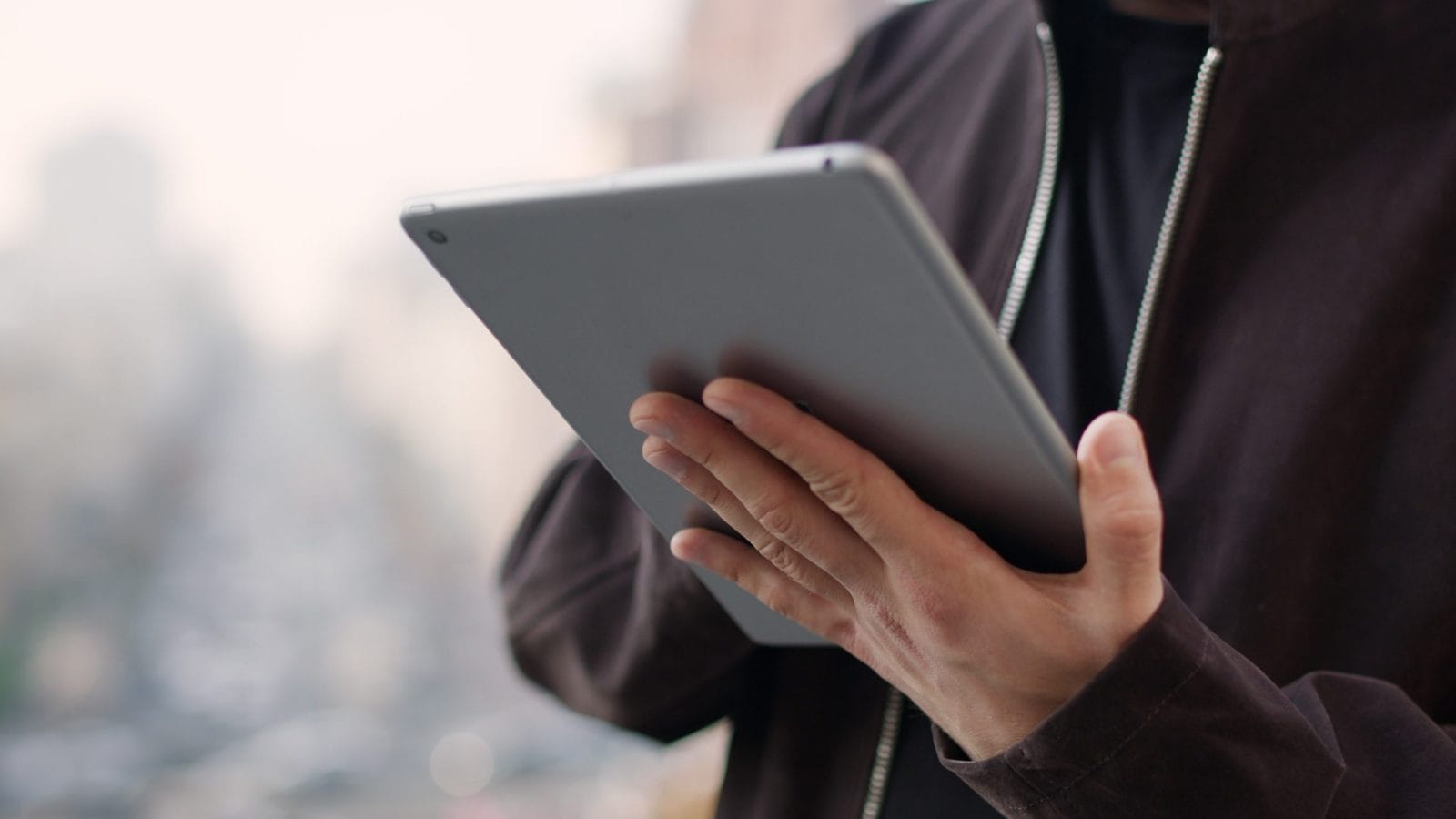 Closeup male hands surfing internet on tablet computer outdoors