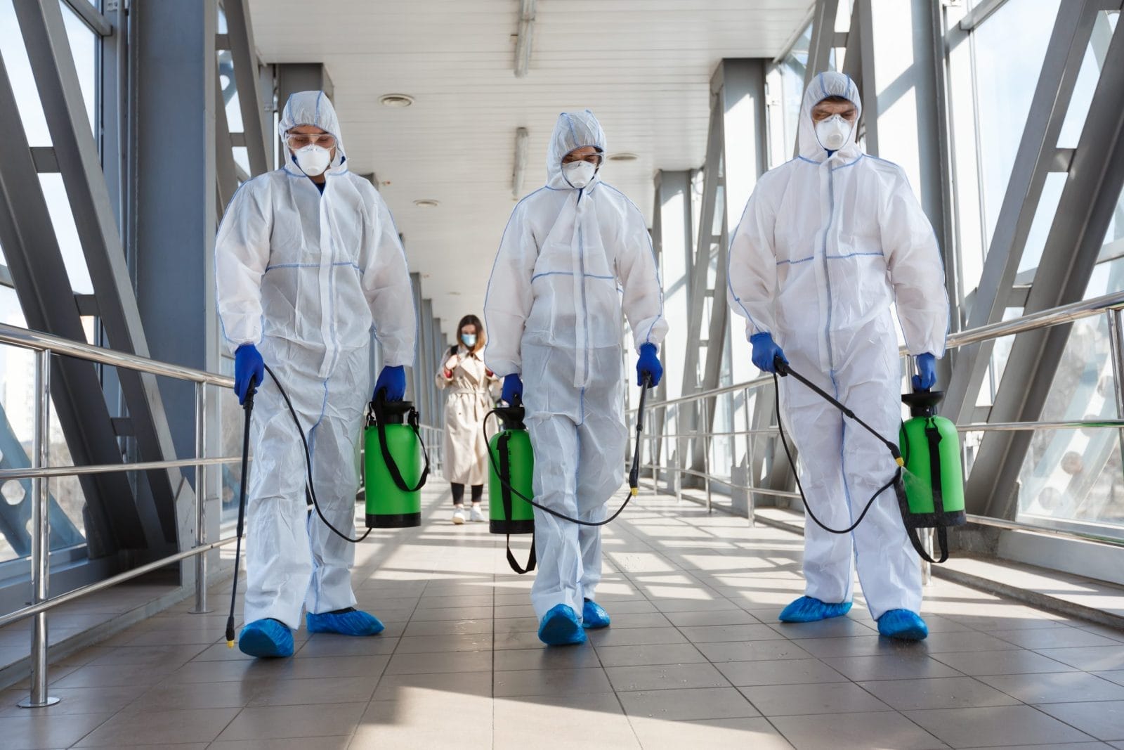 Workers in hazmat suits sanitizing a walkway