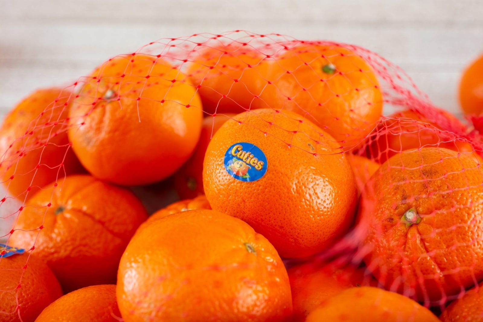 mesh bag full of Cuties mandarins with produce stickers