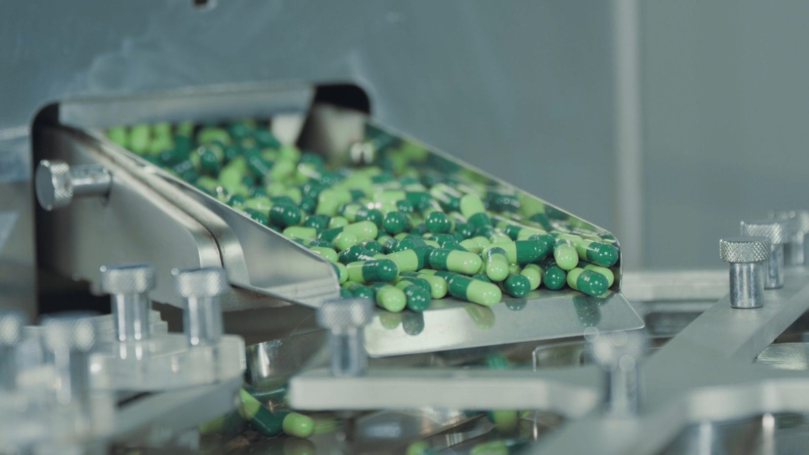 Green capsules move along the metal automatic conveyor