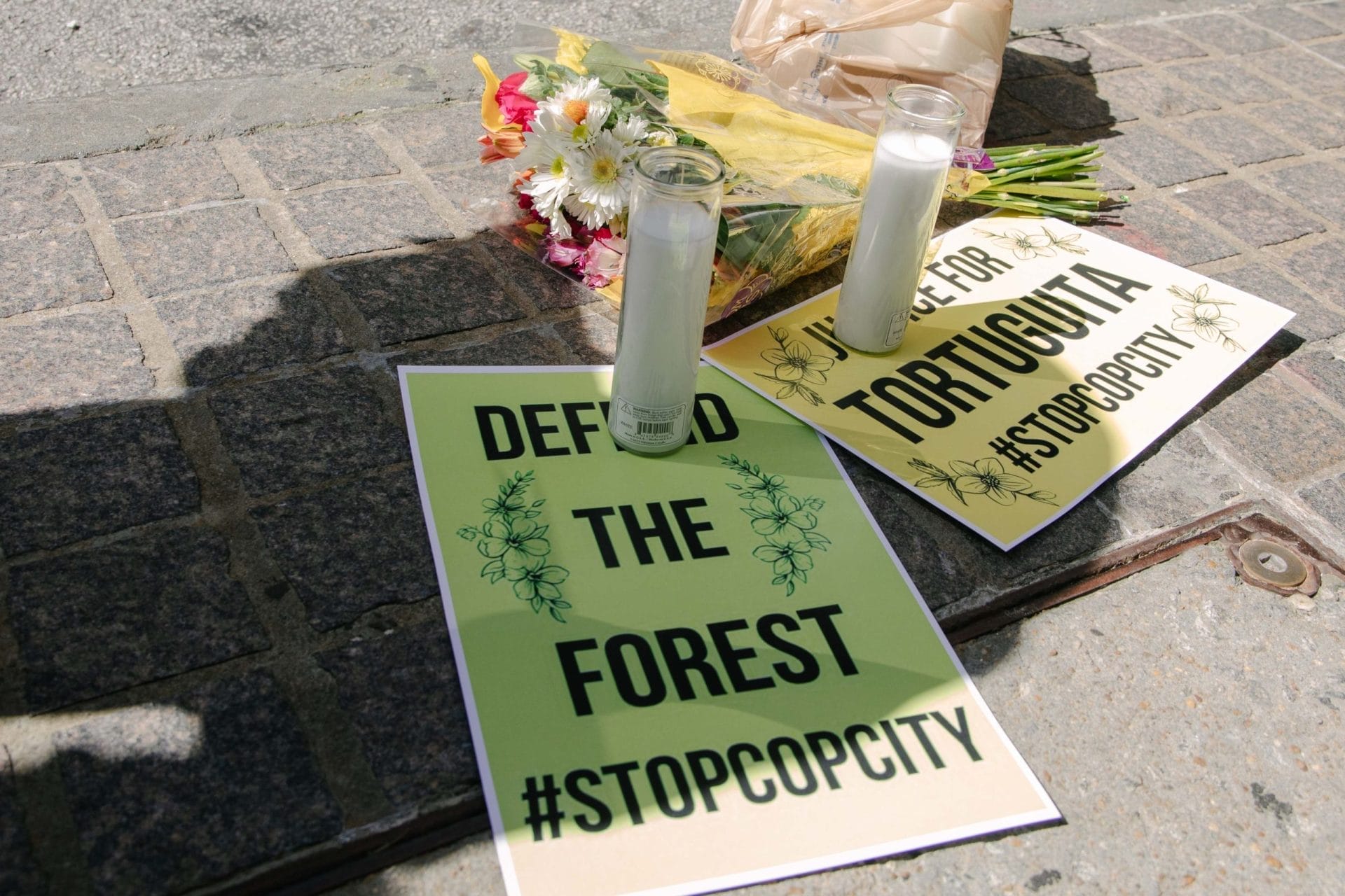 Posters against Cop City lying on the ground next to candles