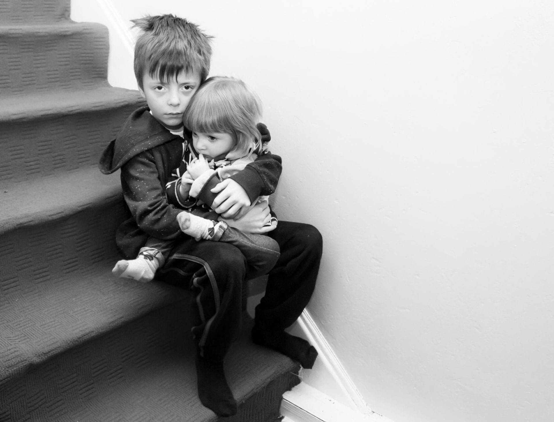 Little boy holding his baby sister on the stairs