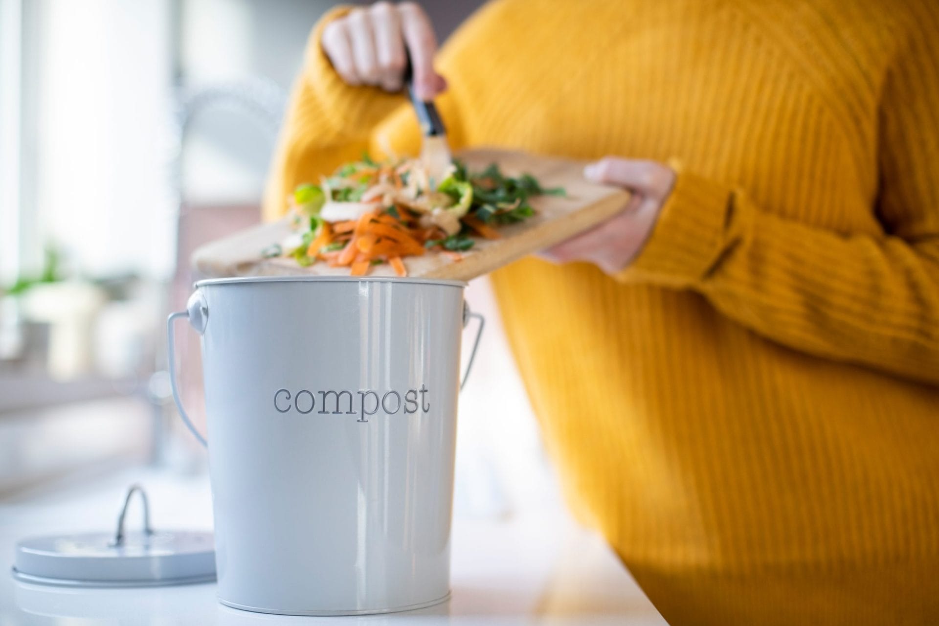 Woman putting food scraps into compost bucket