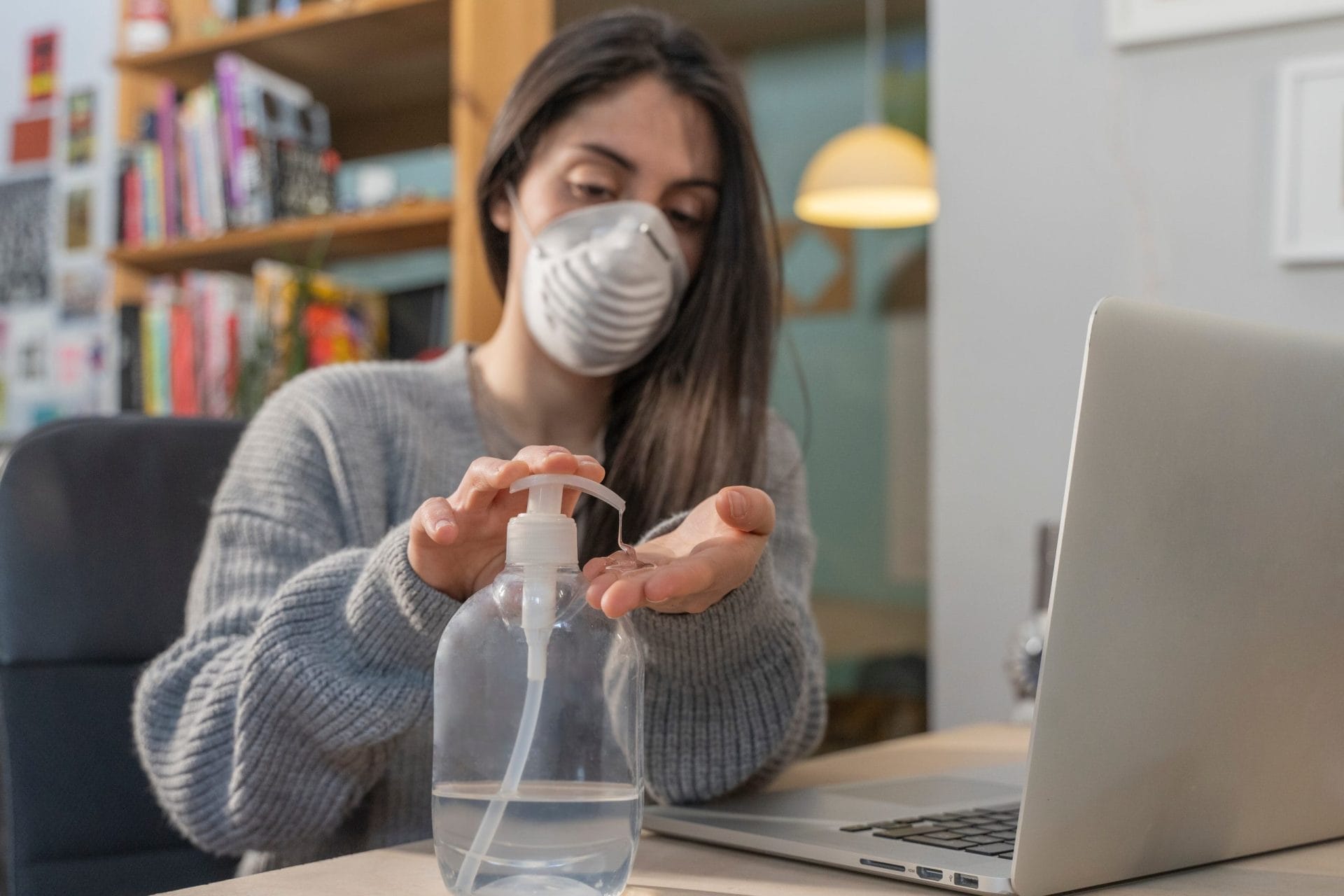 A woman wearing a mask and sanitizing her hands