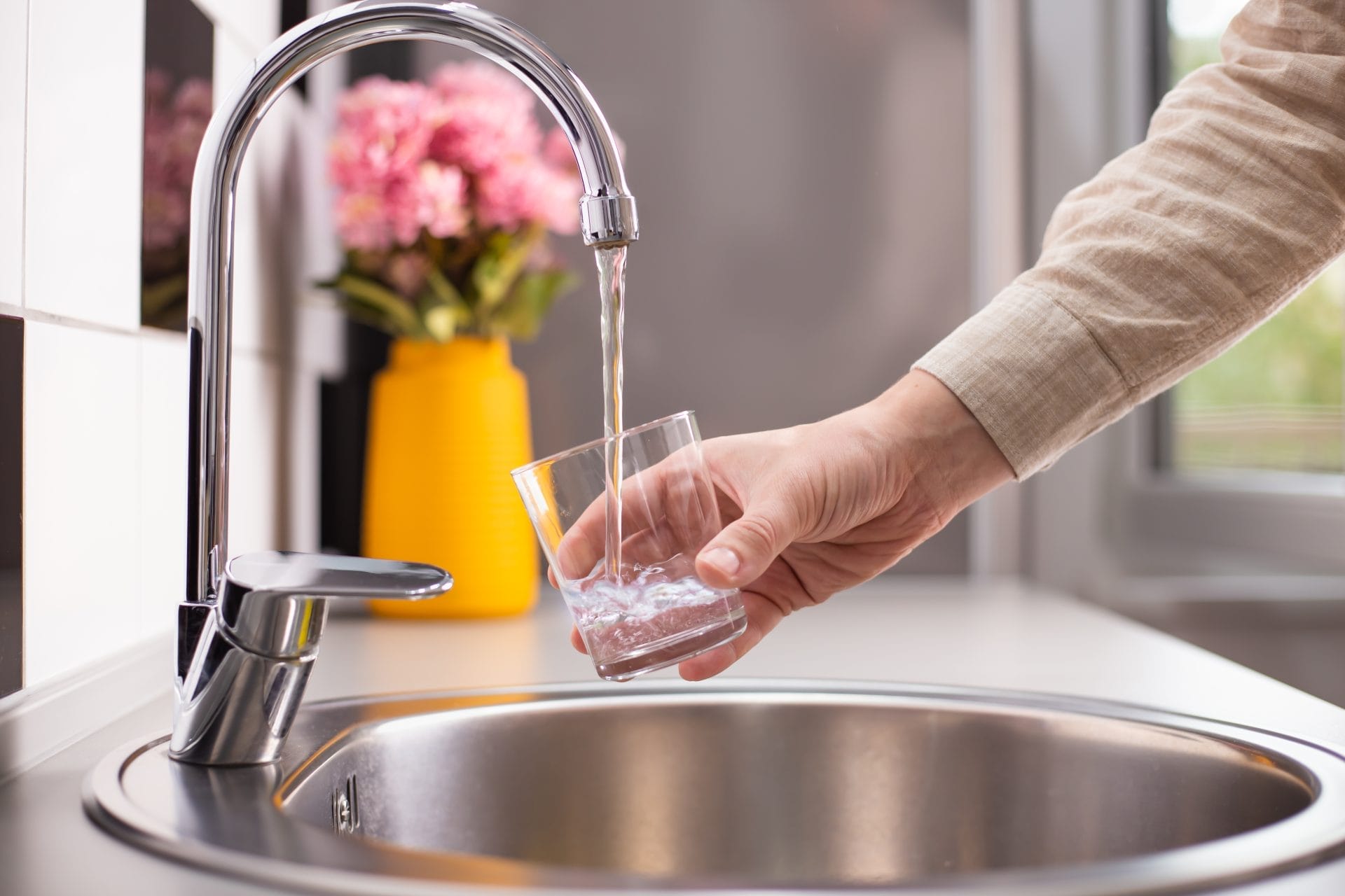 Someone pouring themselves a cup of water from the tap
