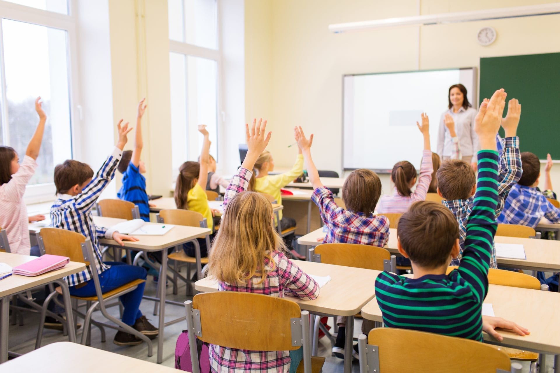 Children raising their hands in class