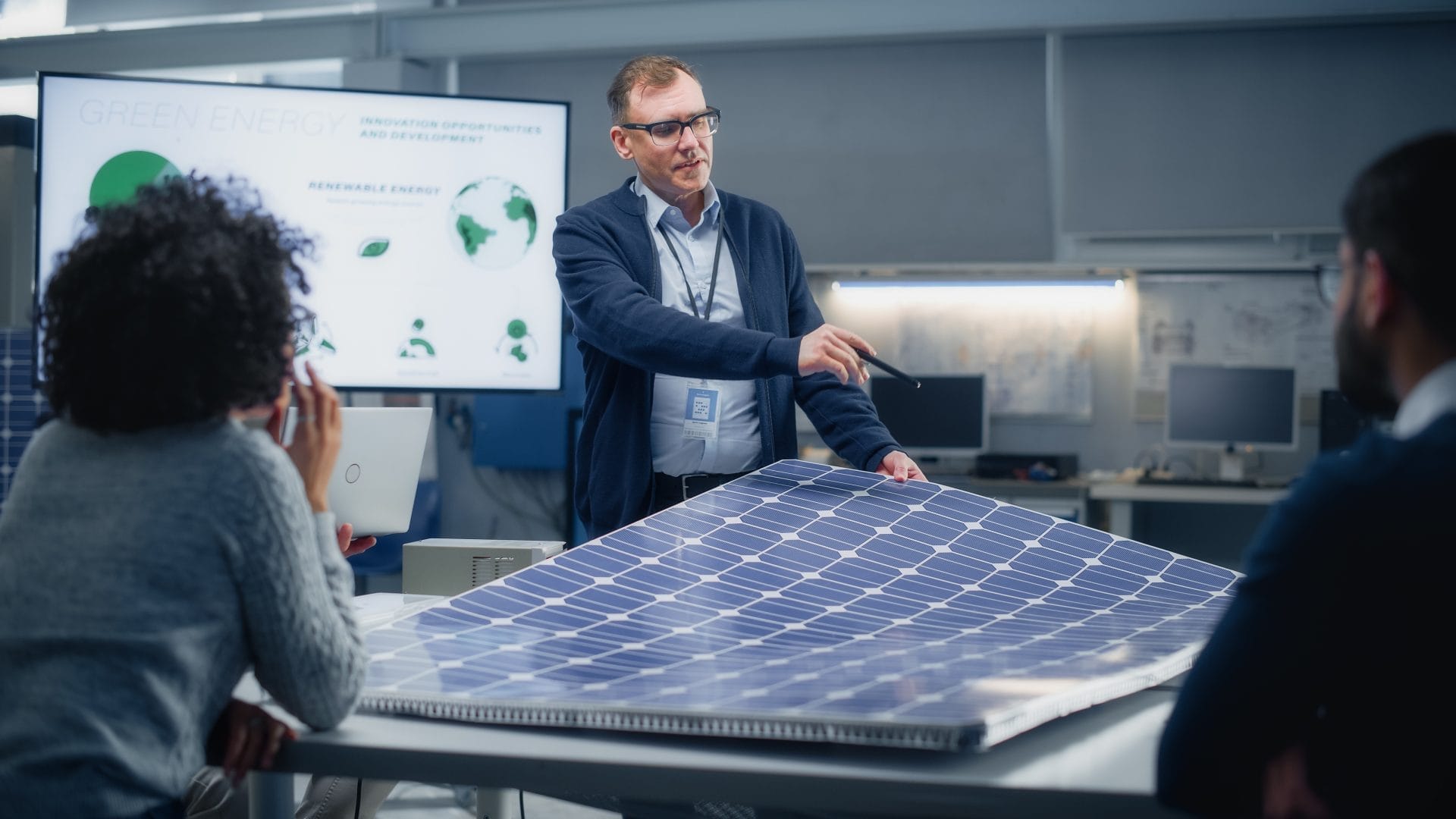 Man talks and points at solar panels in front of students