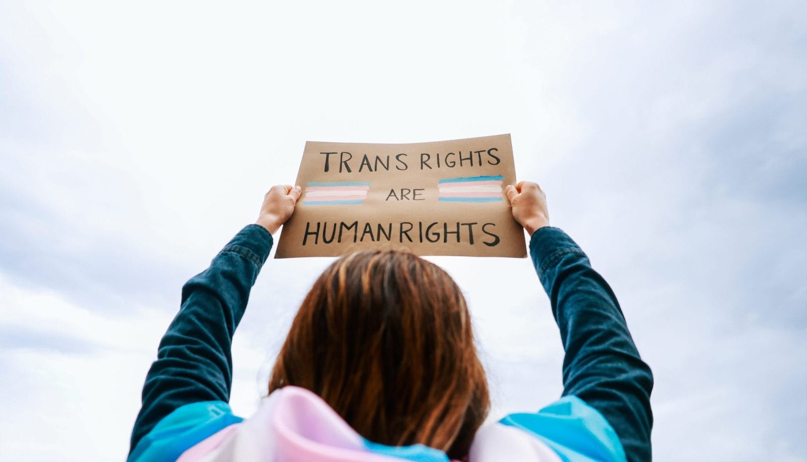 Transgender woman fighting for trans human rights at gay pride protest holding banner - People celebrating LGBTQ festival concept