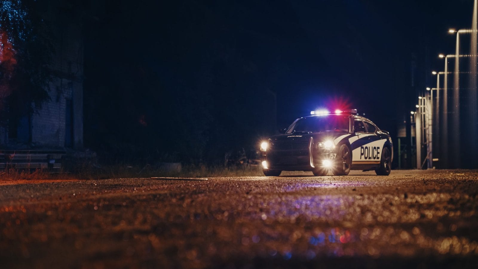 Low Angle Shot of a Stopped Police Car with Lights and Siren on During a Misty Night. Patrolling Vehicle on Stand by, Waiting for Orders to Start Pursuing Suspects. Police Enforcement