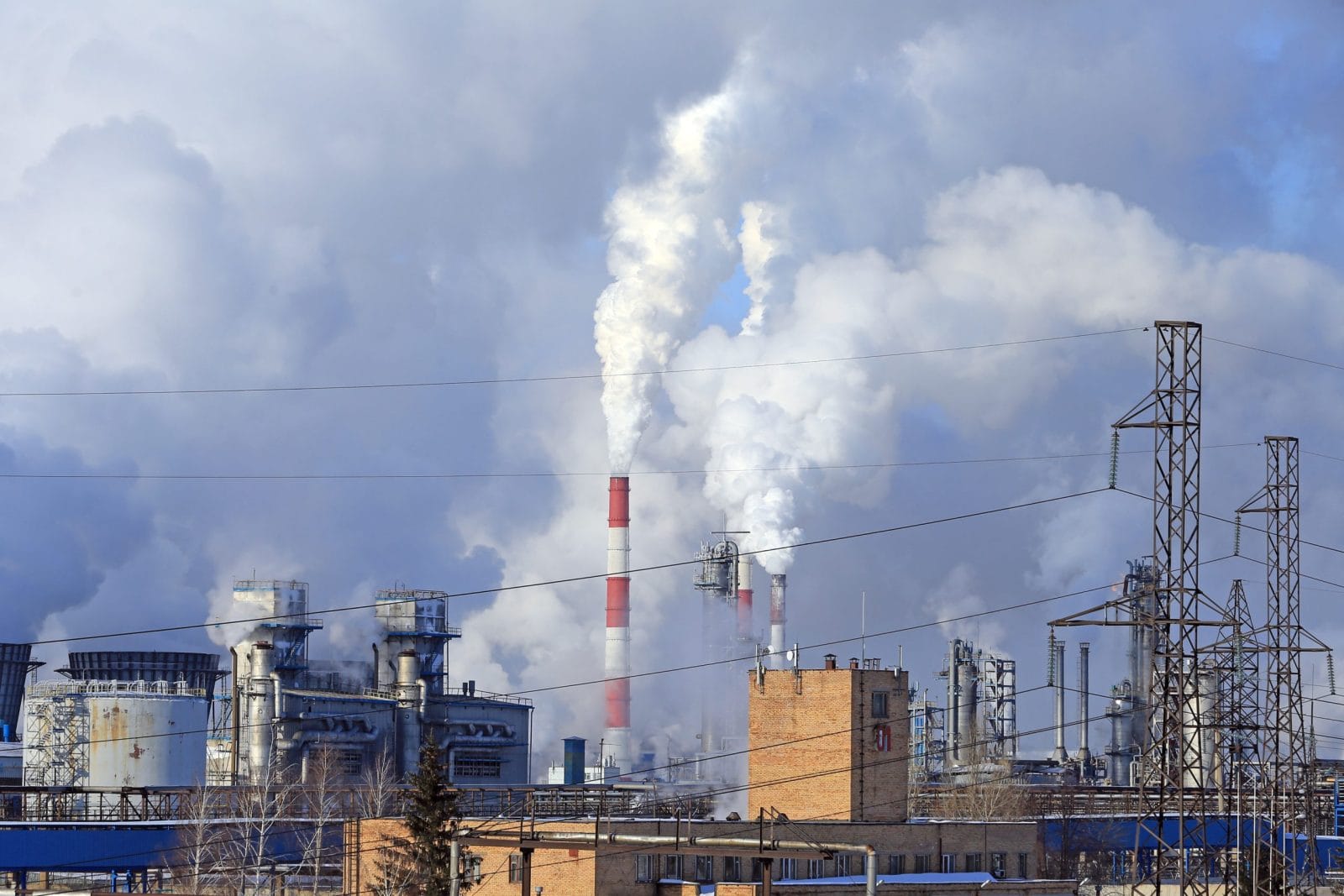 industrial landscape smoke from the chimneys large plant and power lines against the blue sky in winter