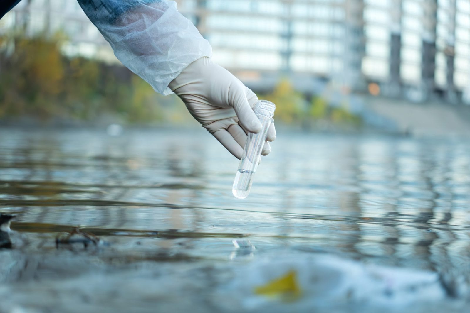 Close up of scientist with white glove holding test tube with water in his hand. Water pollution examine concept