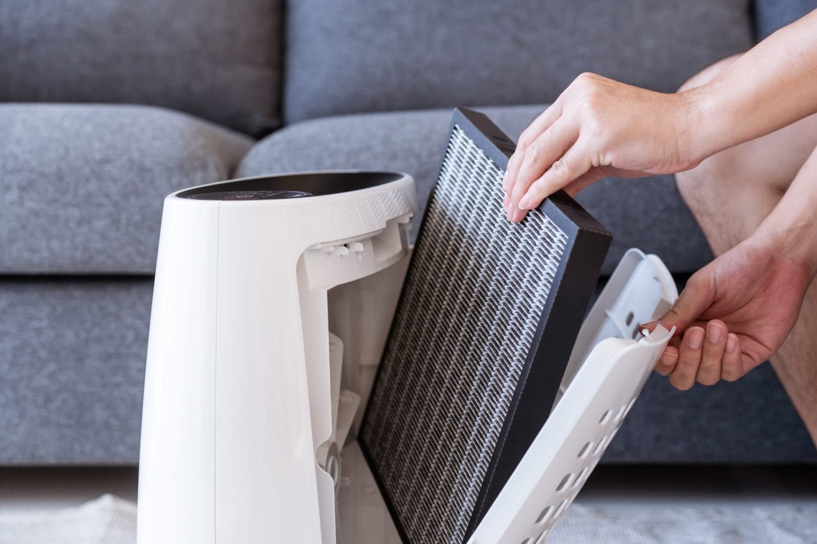 Unrecognizable Asian young man changing - fixing a dirty air purifier HEPA filter after using for a long time. A repairman replacing and installing the air purifier filter. Healthcare and wellbeing.